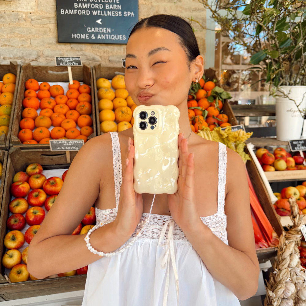 Girl next to a fruit stand holding the 3d bubble butter yellow phone case