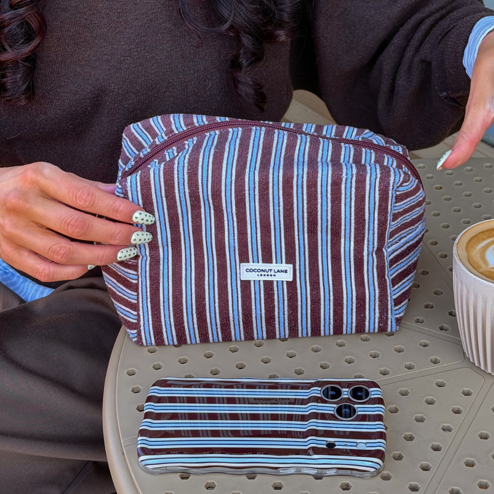 Girl sat at coffee table with a latte and Brown and Blue Stripe Makeup Bag