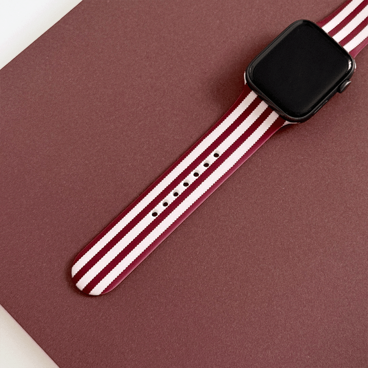 Burgundy and light pink striped Apple Watch Strap, attached to a black Apple Watch.