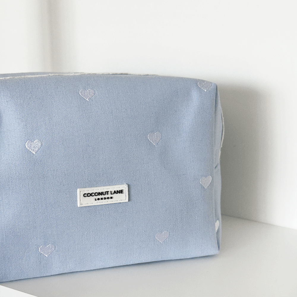 Blue fabric Makeup Bag with embroidered heart design and white lace trim.