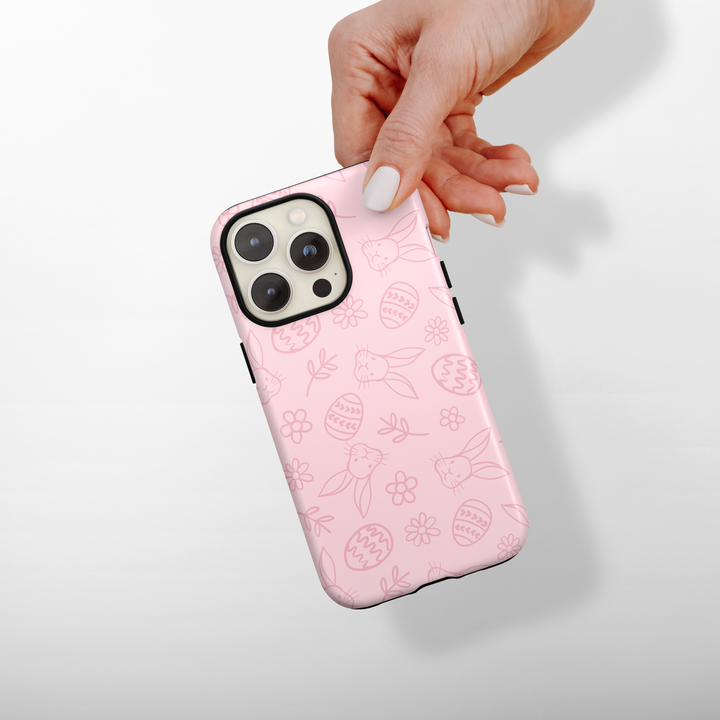 Pink phone case with patterns held by a hand on a light gray background