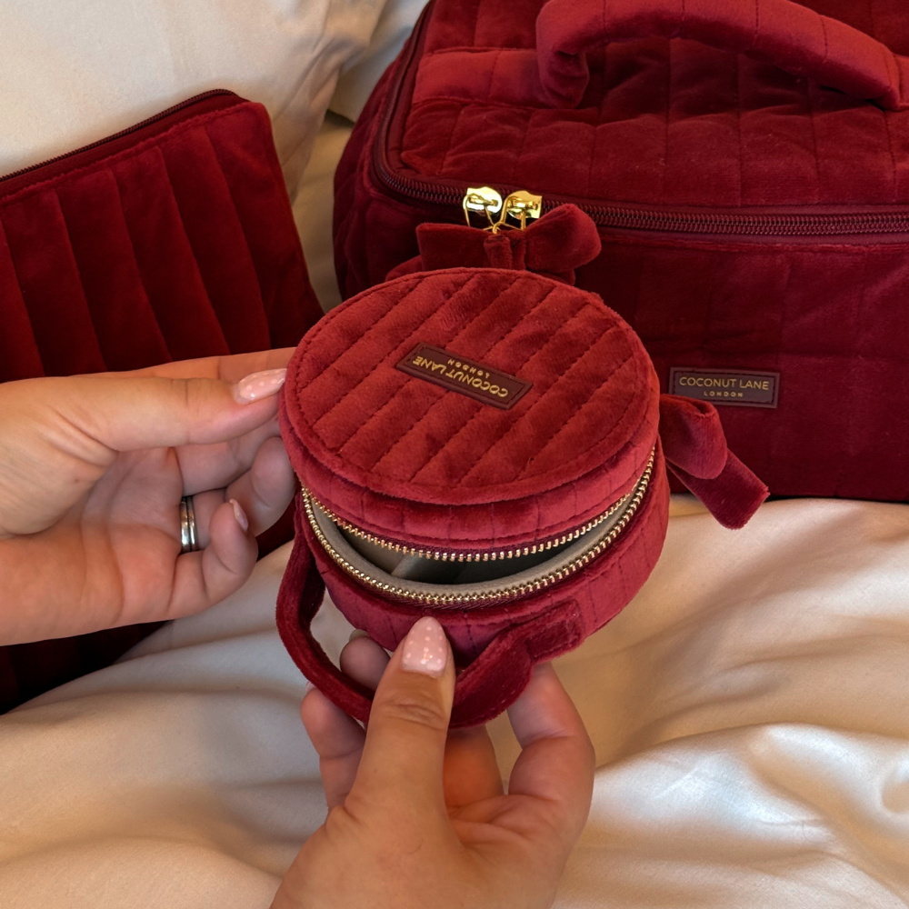 Burgundy velvet jewellery box with a quilted design, top handle, bow detail, and gold-tone hardware.