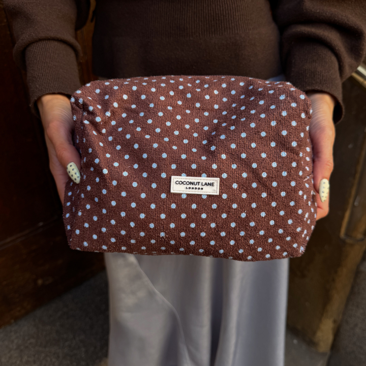 Girl wearing brown and blue holding her brown and blue towel makeup bag