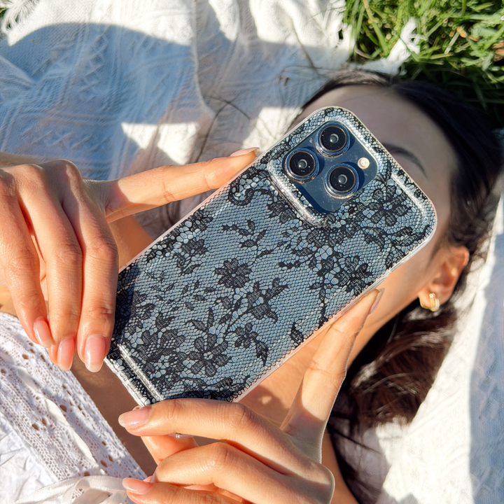 Girl laying down at a picnic holding up her clear black lace phone case