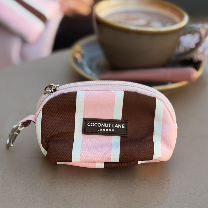 Coconut Lane Cocoa & Pink Stripe mini keyring bag featuring chocolate brown, baby pink and white stripes, placed on a table alongside a coffee.