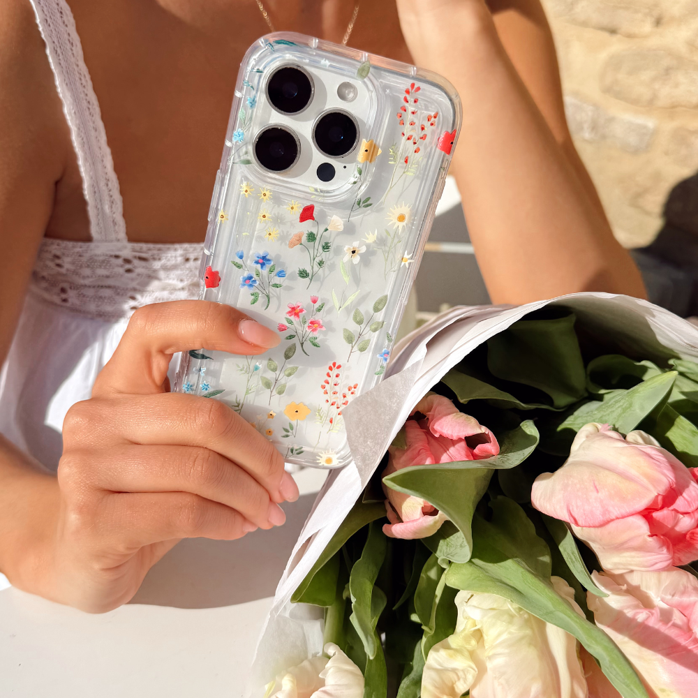 Girl holding her Colourful Wildflower Phone Case next to a bunch of pretty pink flowers