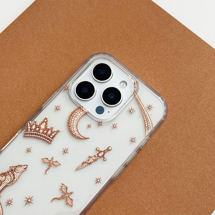 Close-up of Fantasy Girl Clear Phone Case showing intricate rose gold celestial details, including a crown, crescent moon, dagger, dragons and stars, with clear edges and triple camera cutouts.