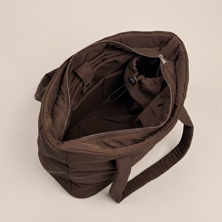Overhead view inside the chocolate brown padded carryall bag, showing the zip fastening, internal pockets, compartments and padded shoulder straps.