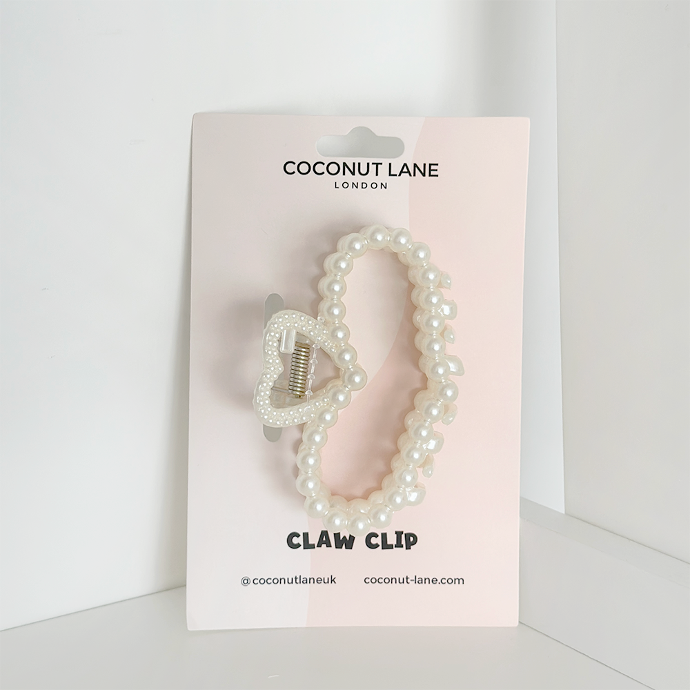 A chic addition to your collection, the Pearl Heart Claw Clip from Coconut Lane is adorned with pearl beads and attached to a light pink display card featuring white lettering. The card showcases the brand's name and social media handle "@coconutlaneuk".