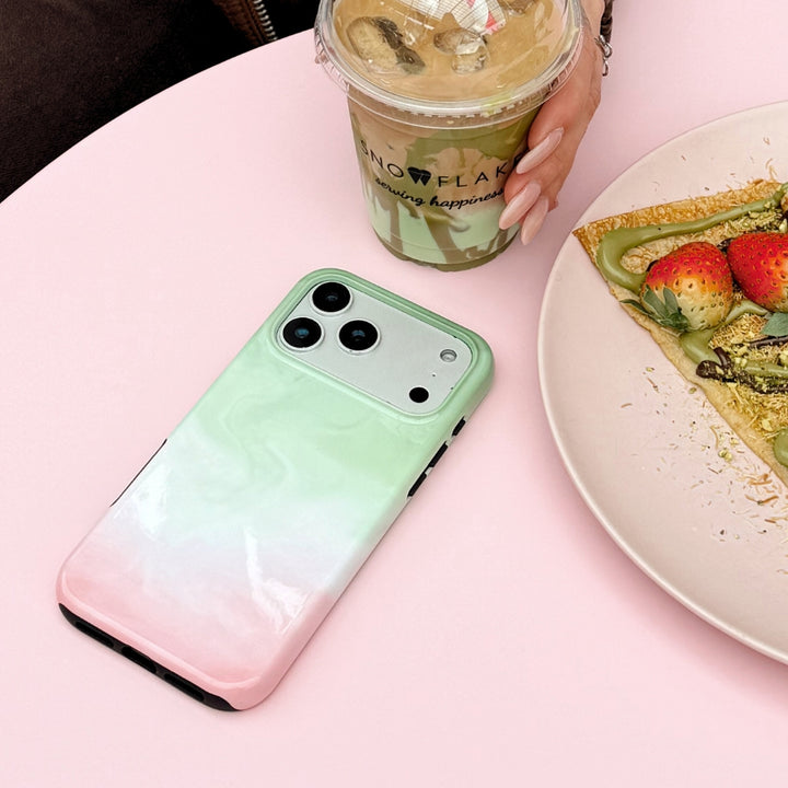 Strawberry Matcha Tough Phone Case on a pink table next to a matcha and a crepes.