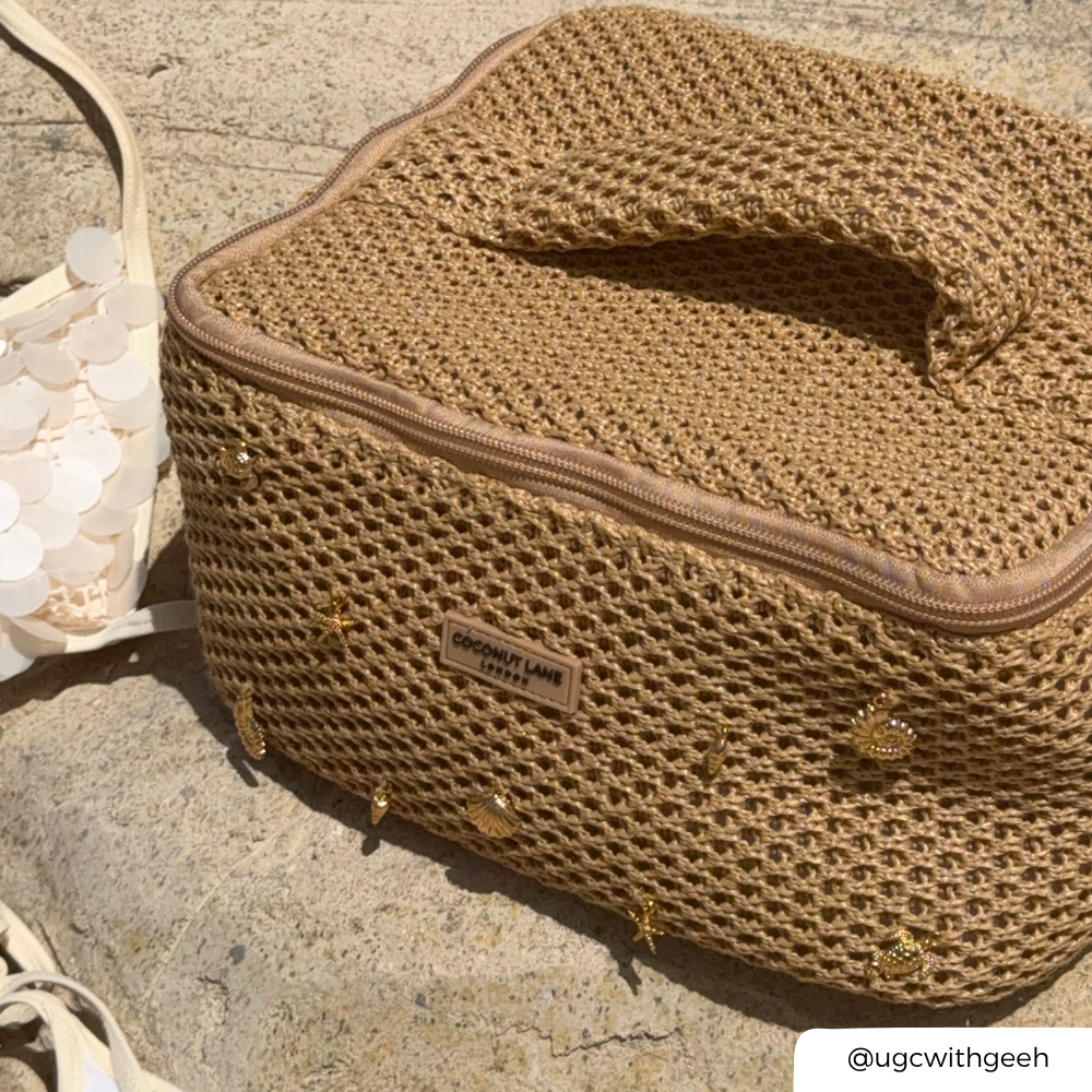 Brown woven makeup bag with a visible brand label on a textured surface with shells