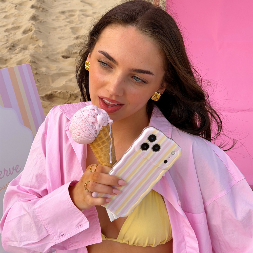 Girl licking ice cream on the beach in her bikini holding the Wavy Pastel Stripes Phone Case