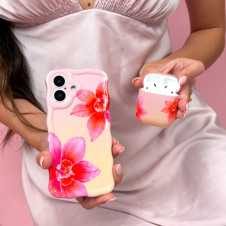 Girl holding matching pink orchid sunset phone case and airpods case