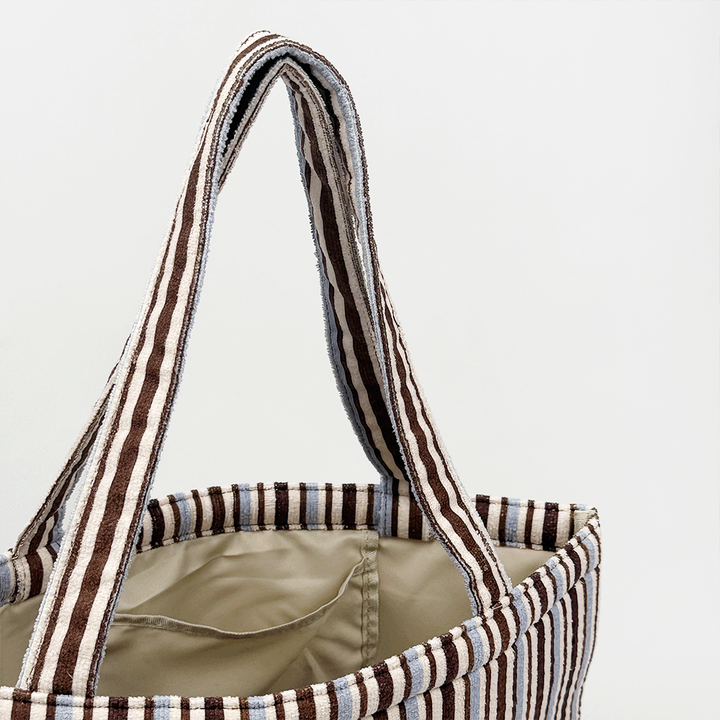 Brown and blue striped tote bag with beige, towel-like interior lining.