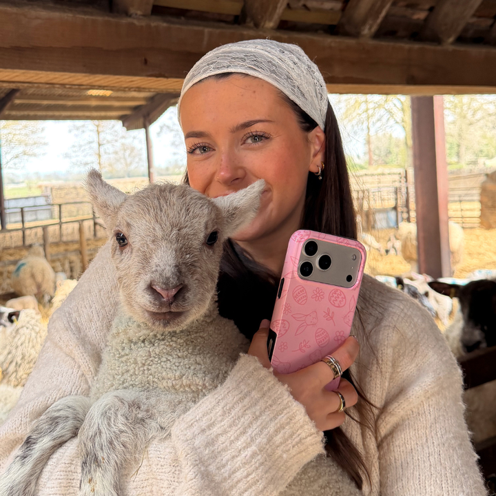 Girl smiling holding lamb and blush bunny tough phone case in hand