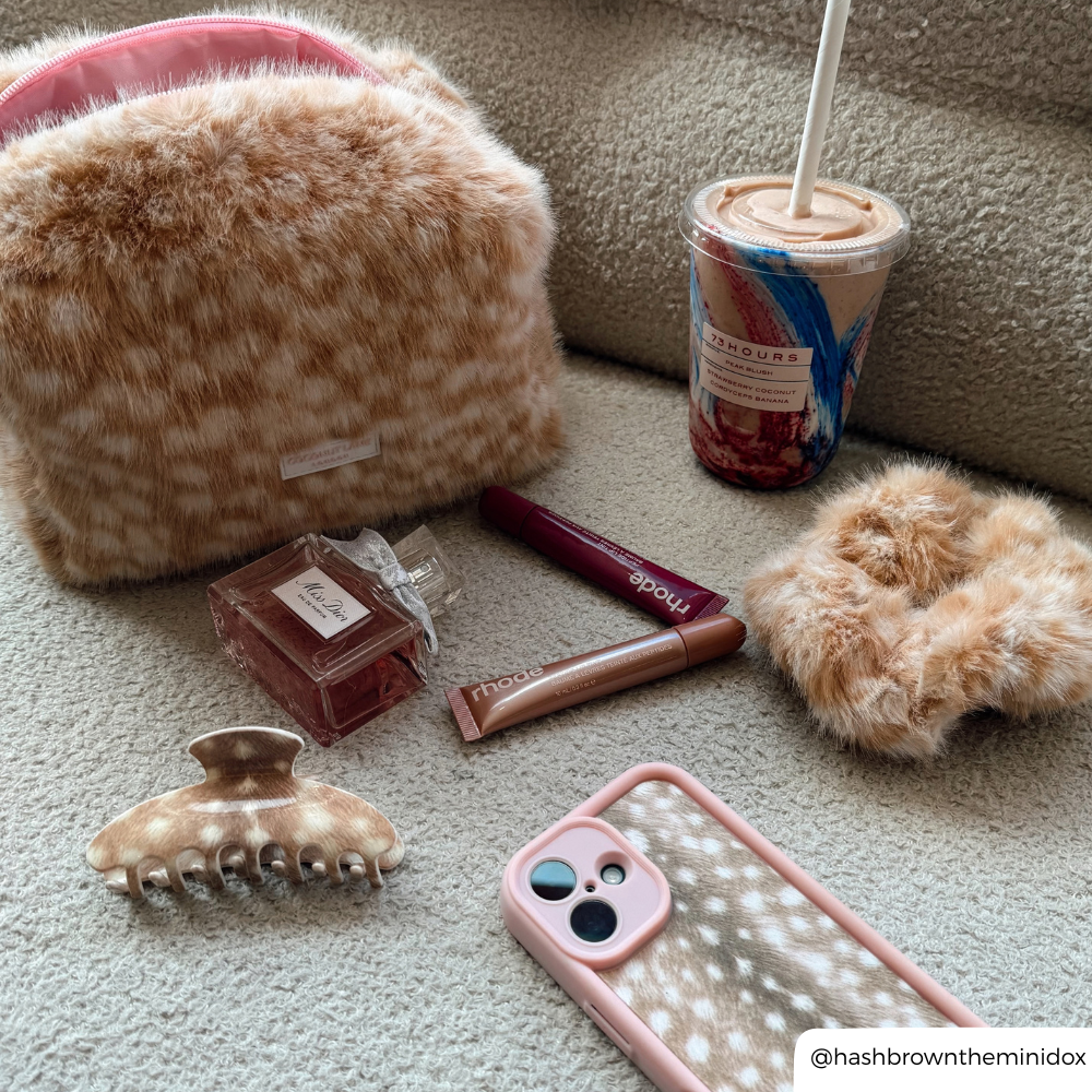 Fawn makeup products on a boucle sofa, makeup bag, claw clip, scrunchie and phone case all match