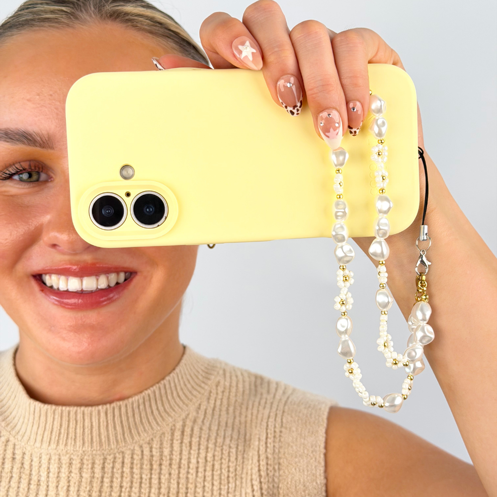 Girl smiling holding butter soft yellow phone case with pearl core phone strap attached