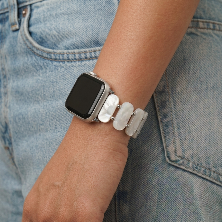 Girl wrist next to jean pocket wearing white pearl beaded watch strap