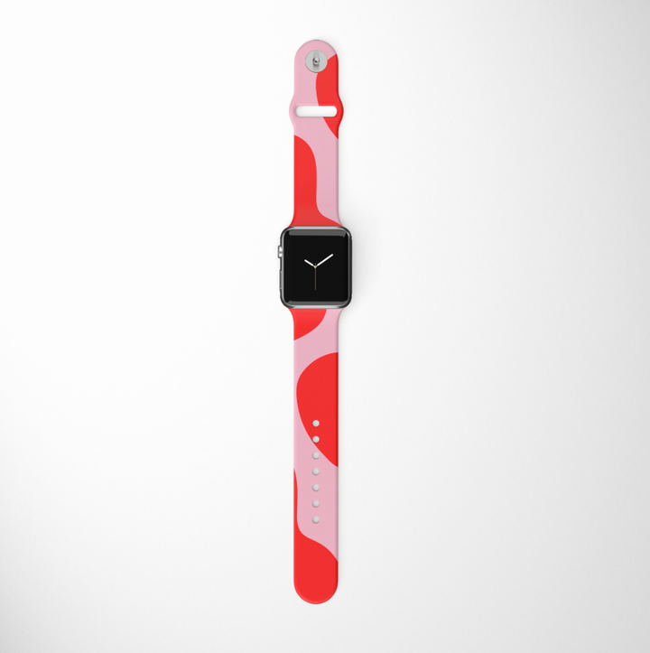 A Coconut Lane smartwatch comes with an Abstract Pink & Red Apple Watch Strap, showcasing a vibrant mix of pink and red tones against a white background. The watch face is black with straightforward white hands for a minimalistic look, and the band includes multiple adjustment holes along with a silver clasp.